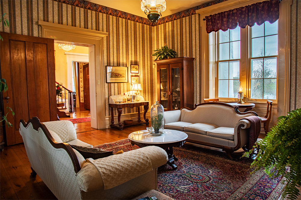 Front Parlor, double antique white sofas, fire place and large windows